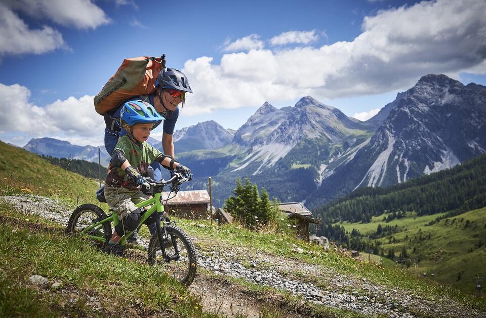 Mother and child enjoy a bike ride together amidst the majestic mountain landscape of Arosa